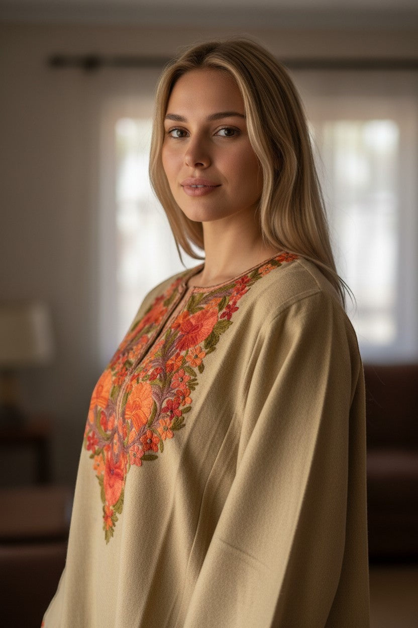 Kashmir Gallery beige woolen pheran with vibrant floral Aari embroidery around the neckline. A woman models the traditional garment.